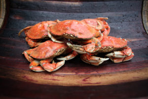 pile of five freshly cooked red dungeness crabs on old wooden seat by Don Frank Photography