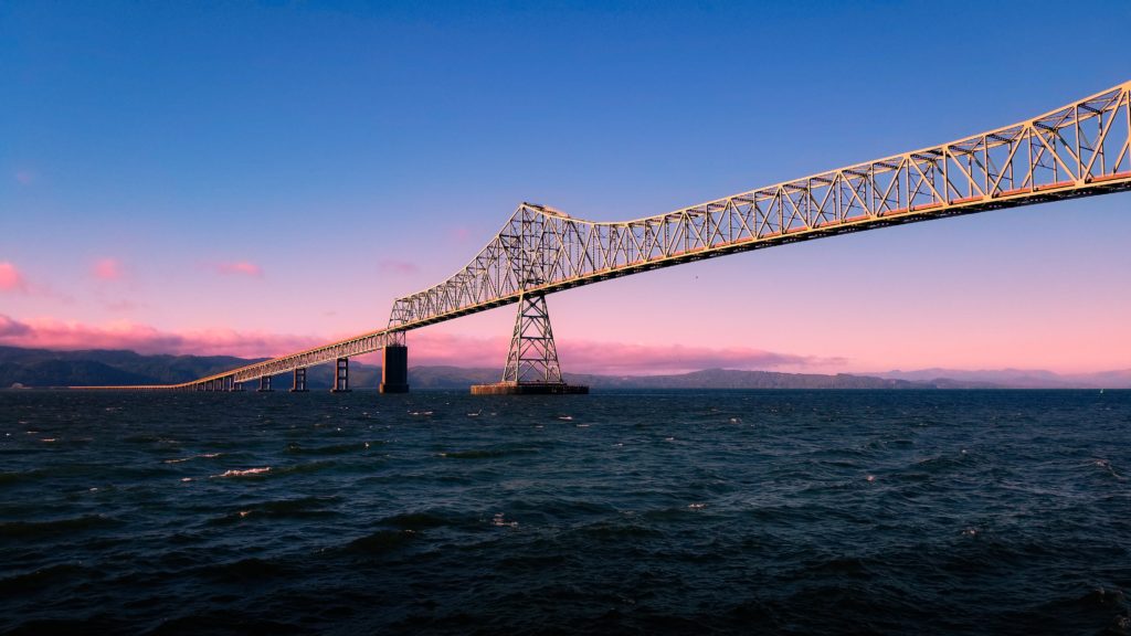 The Astoria-Megler Bridge crossing the Columbia River under a blue and pink sky.