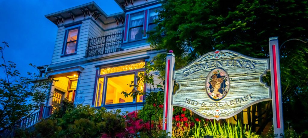 Exterior of large white house with blue trim - ornate wooden sign which reads Clementine's Bed & Breakfast