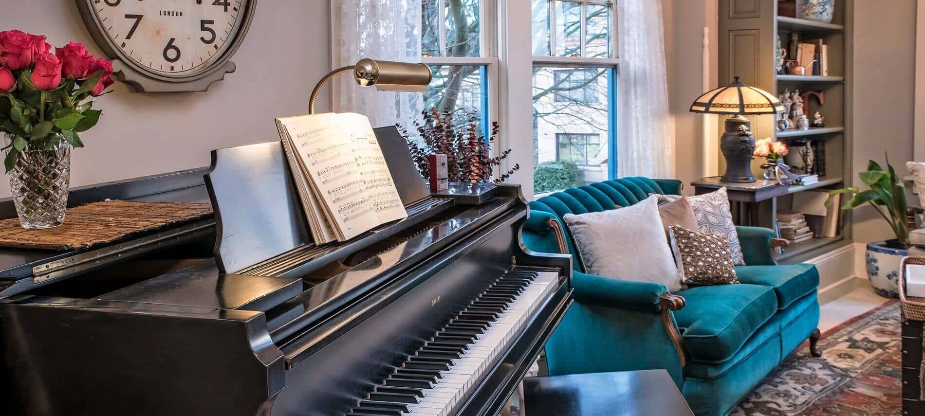 Sitting area with a teal colored sofa and a black piano. 